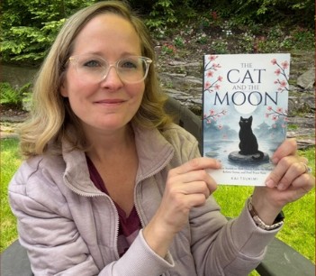 A reader outdoors holding The Cat and the Moon